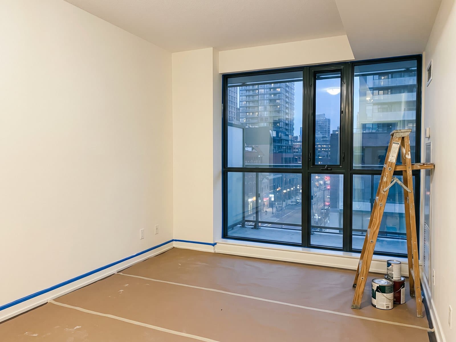 Condo living room with floor-to-ceiling windows and freshly painted off-white walls, concept imagery